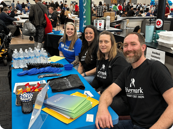 Rivermark employees sitting at a table at an event.