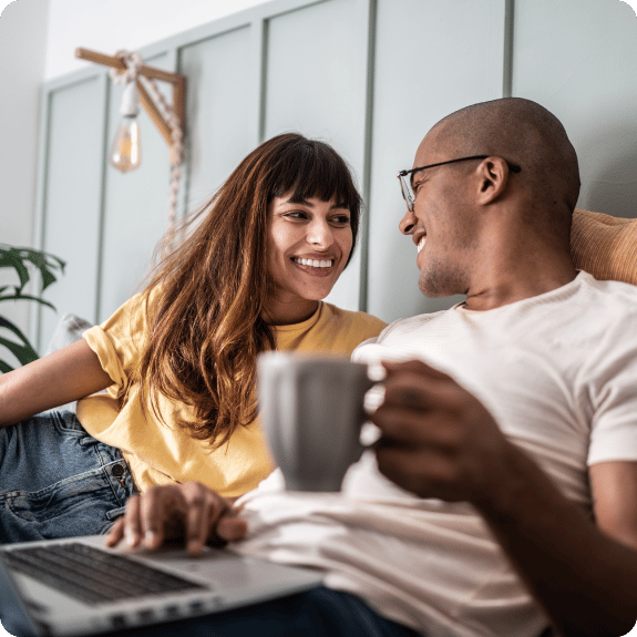 Couple sitting on the couch together drinking coffee.