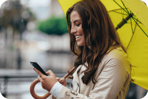 Woman with a yellow umbrella looking at her phone.